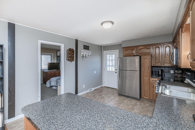 kitchen featuring dark countertops, visible vents, decorative backsplash, stainless steel appliances, and a sink