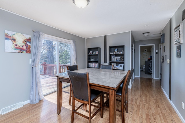 dining area featuring visible vents, baseboards, and light wood finished floors