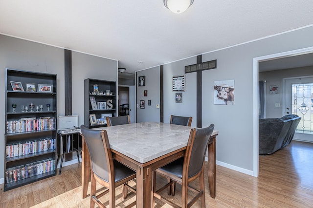 dining space featuring baseboards and light wood finished floors