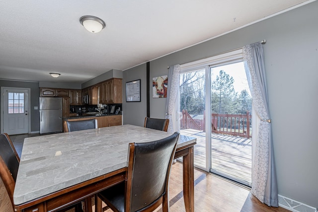 dining room with light wood-style floors, visible vents, and baseboards