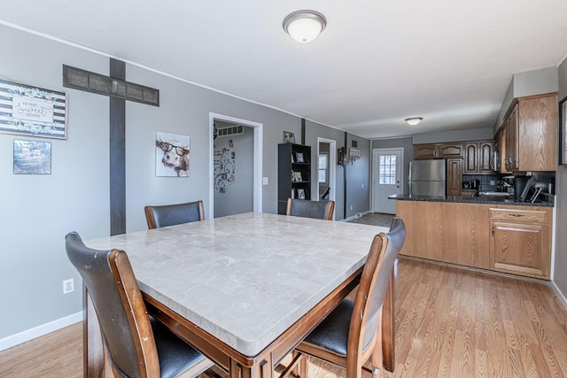 dining room featuring light wood-style flooring and baseboards