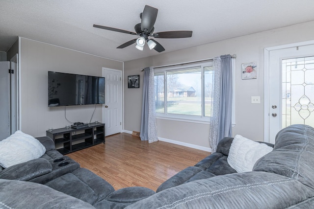 living room with baseboards, a textured ceiling, a ceiling fan, and wood finished floors