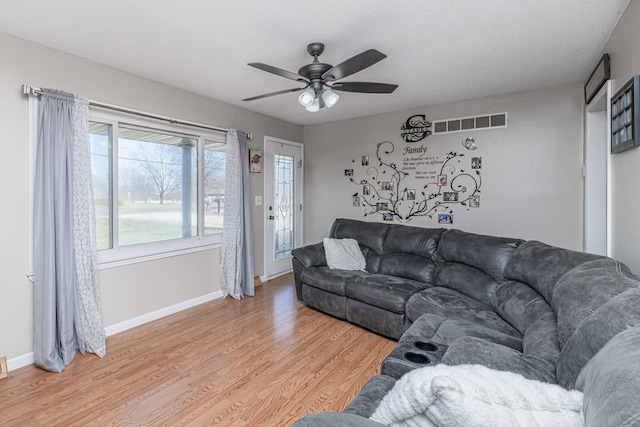 living room with visible vents, a ceiling fan, a textured ceiling, light wood finished floors, and baseboards