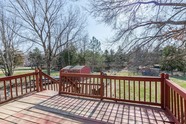 wooden terrace featuring a shed, an outdoor structure, a yard, and fence