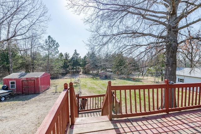 wooden terrace featuring an outdoor structure, a yard, and a storage unit