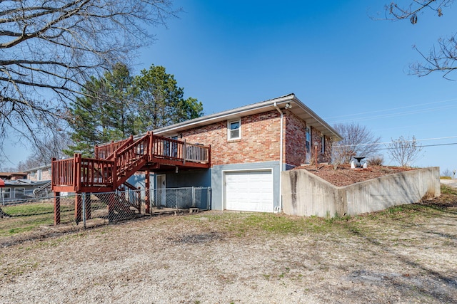 back of house with fence, stairway, a wooden deck, a garage, and brick siding