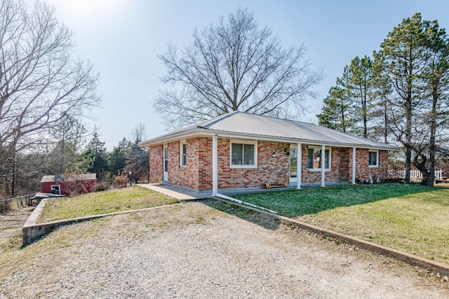 view of front of home featuring brick siding, metal roof, and a front yard