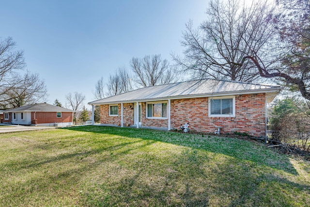 ranch-style house with brick siding, metal roof, and a front lawn