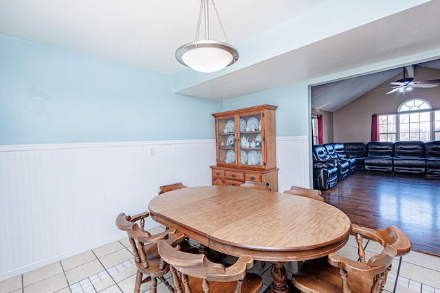 dining room featuring vaulted ceiling with beams, a ceiling fan, a wainscoted wall, and light tile patterned flooring