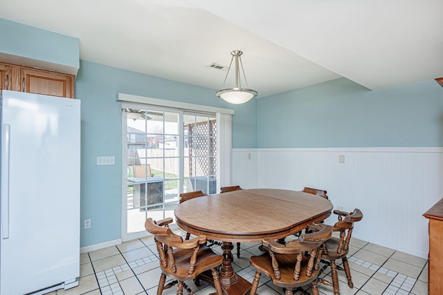 dining room with light tile patterned floors, visible vents, and wainscoting