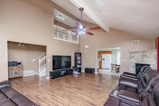 living area featuring ceiling fan, visible vents, beamed ceiling, and light wood-style flooring