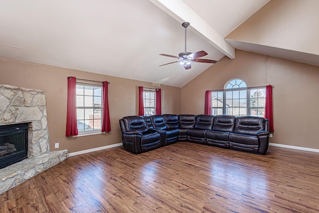 living room with baseboards, lofted ceiling with beams, a fireplace, a ceiling fan, and wood-type flooring