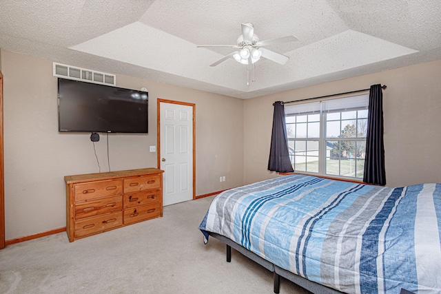 bedroom featuring a raised ceiling, carpet, visible vents, and a textured ceiling