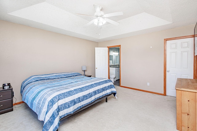 bedroom with a raised ceiling, a textured ceiling, baseboards, light colored carpet, and ceiling fan