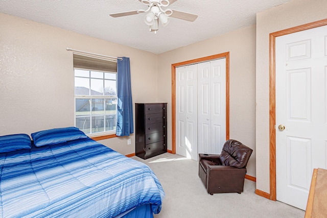 carpeted bedroom with a closet, baseboards, a textured ceiling, and ceiling fan