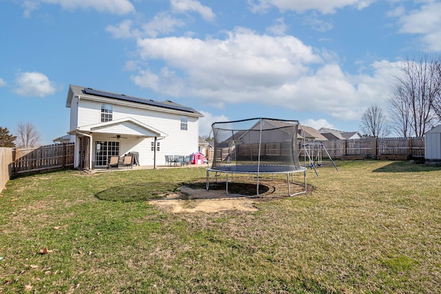 view of yard featuring a ceiling fan, a trampoline, a fenced backyard, a playground, and a patio area