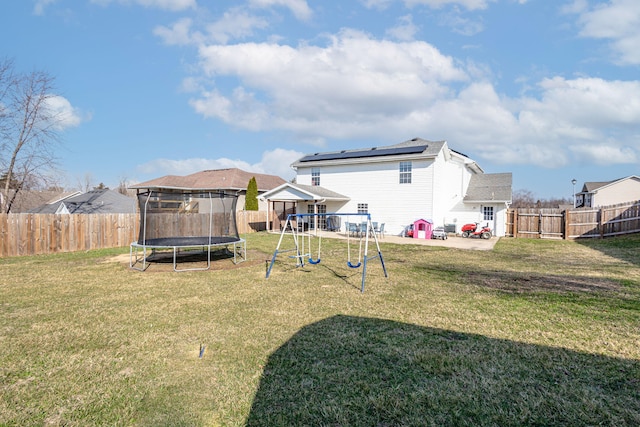 back of property featuring a yard, a fenced backyard, a playground, and a trampoline