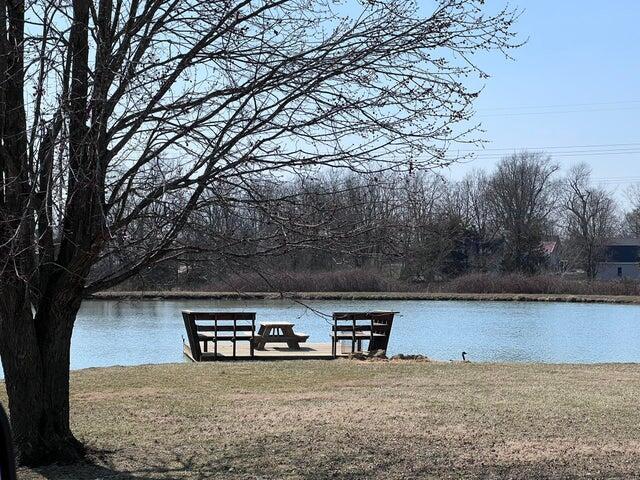 view of dock with a lawn and a water view