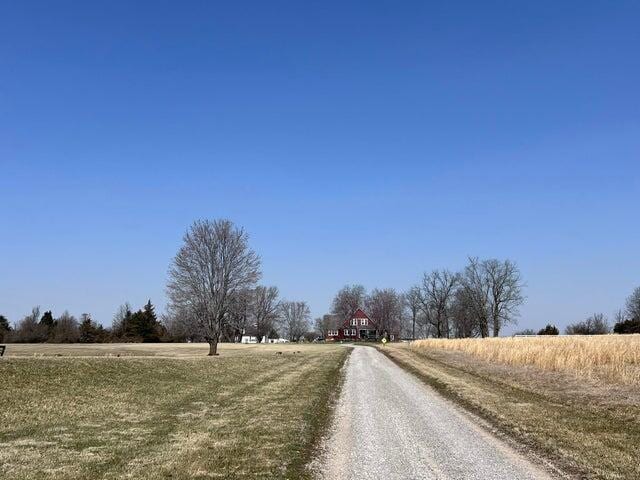 view of street with a rural view and gravel driveway