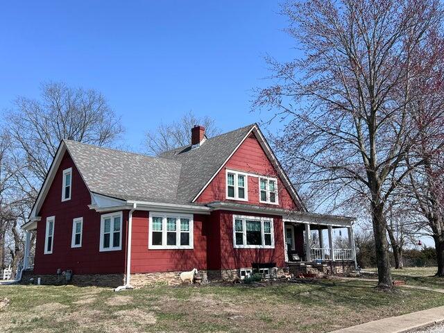 view of front of home featuring a porch, a front yard, roof with shingles, and a chimney