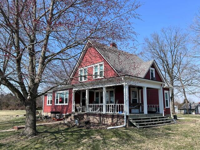 view of front of property featuring a chimney, covered porch, and a front lawn