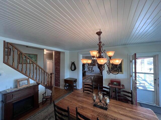 dining room featuring wood finished floors, stairs, wood ceiling, crown molding, and a chandelier