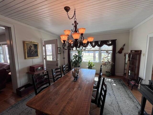 dining room featuring an inviting chandelier, wood finished floors, baseboards, and ornamental molding