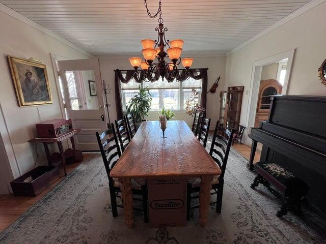 dining area featuring a notable chandelier, wood finished floors, and ornamental molding