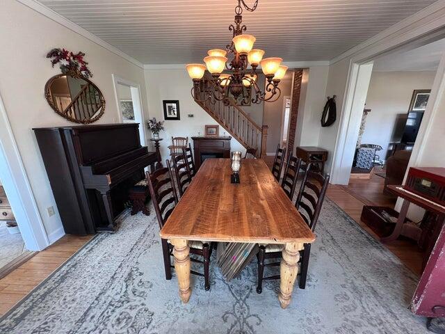 dining space featuring stairs, a notable chandelier, crown molding, and light wood finished floors