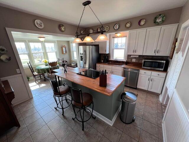 kitchen featuring a kitchen bar, decorative backsplash, appliances with stainless steel finishes, white cabinetry, and a sink