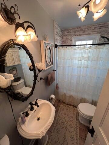 full bathroom with a shower with curtain, toilet, and a sink