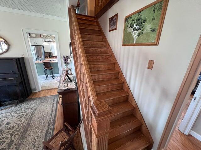 stairway with crown molding and wood finished floors