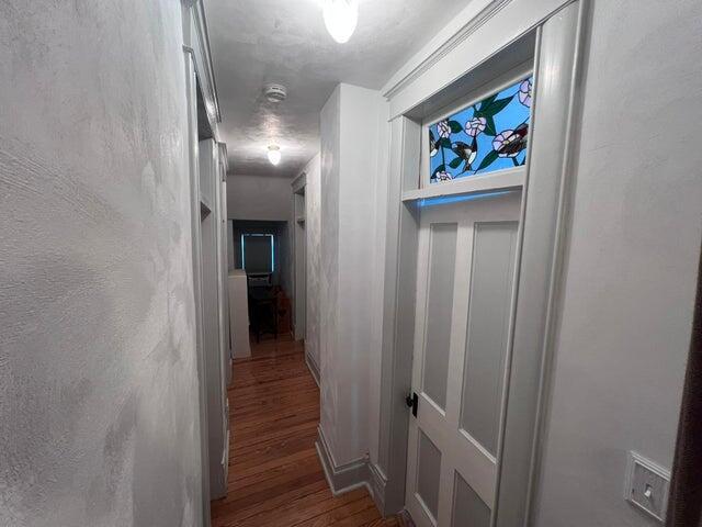 hall with a textured wall and wood finished floors