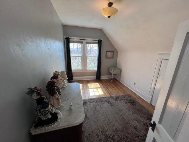 additional living space with lofted ceiling, wood finished floors, and baseboards