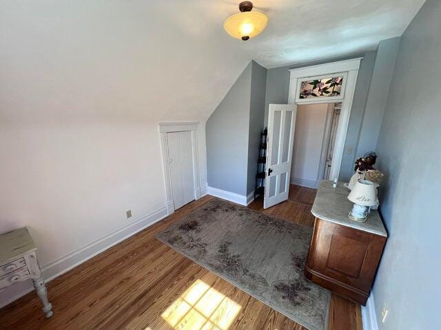 additional living space featuring vaulted ceiling, wood finished floors, and baseboards