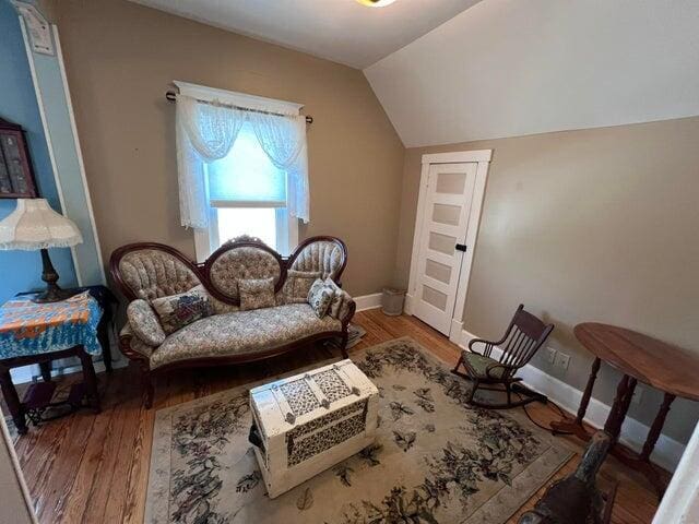 sitting room with wood finished floors, baseboards, and vaulted ceiling