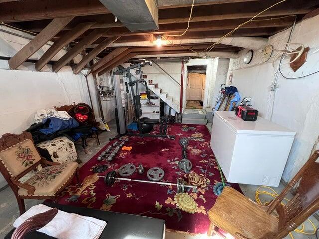 unfinished basement with fridge and stairway