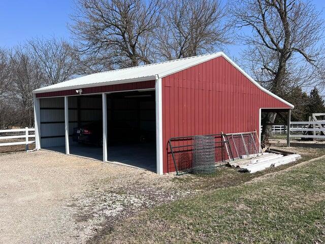 view of pole building with a carport, fence, and driveway