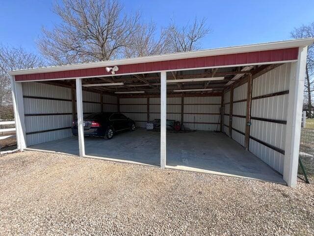 view of vehicle parking featuring a detached carport, driveway, and a pole building