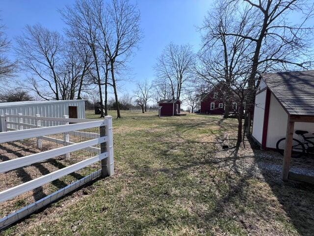 view of yard featuring a storage shed, fence, and an outbuilding