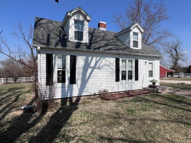 view of property exterior with a yard, a chimney, and fence