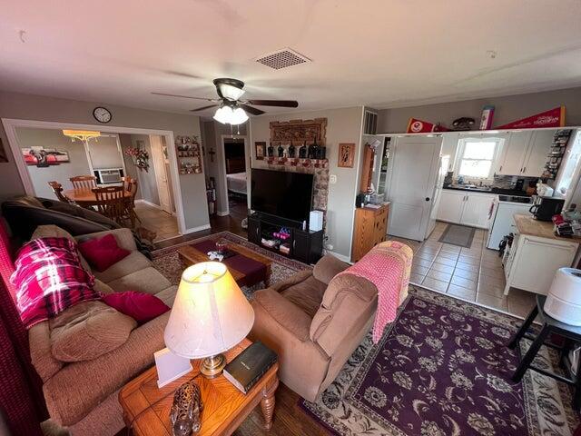 living room featuring tile patterned floors, visible vents, and a ceiling fan