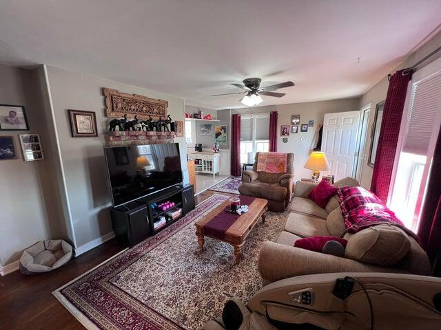 living area featuring baseboards, wood finished floors, and a ceiling fan