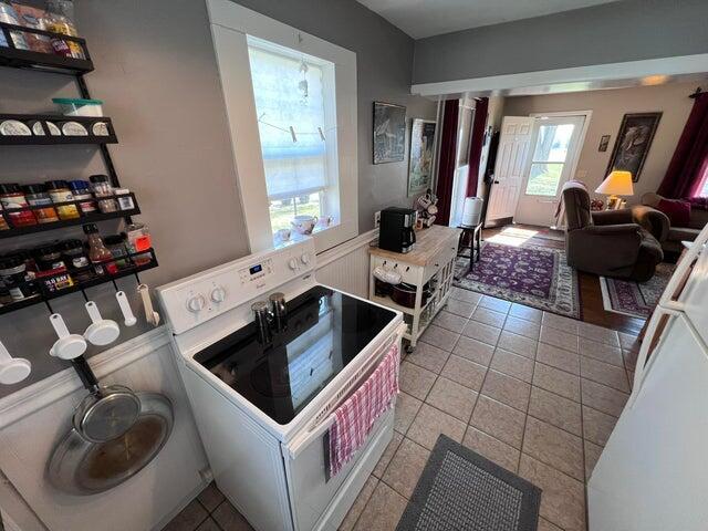 kitchen with white electric stove, open floor plan, and tile patterned flooring