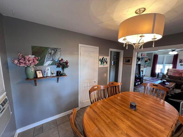 tiled dining area with baseboards and a chandelier