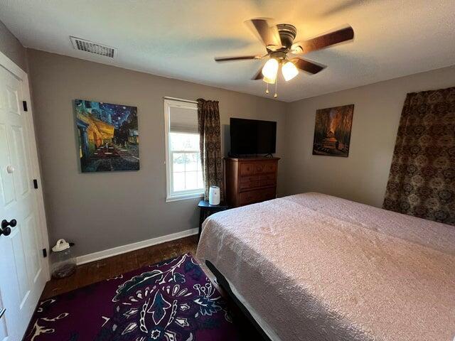 bedroom with visible vents, a ceiling fan, baseboards, and dark wood-style flooring