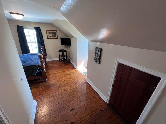 bedroom with baseboards, lofted ceiling, and hardwood / wood-style floors