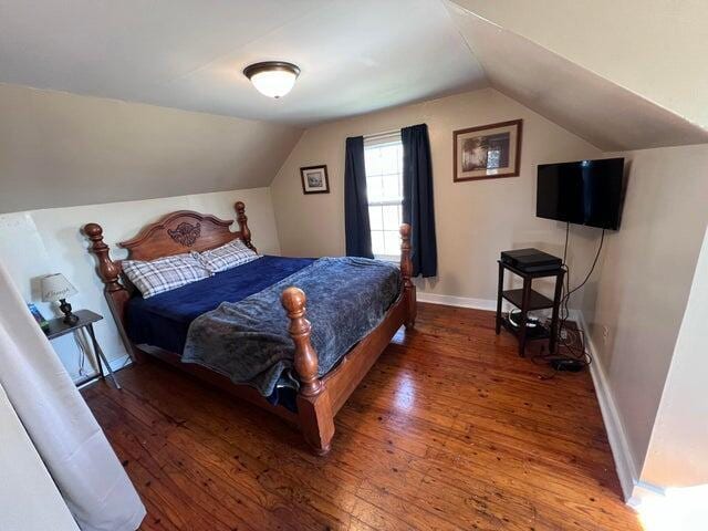 bedroom featuring vaulted ceiling, baseboards, and wood-type flooring