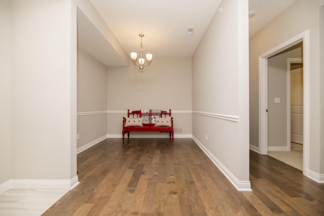 hall featuring baseboards, a notable chandelier, and wood finished floors