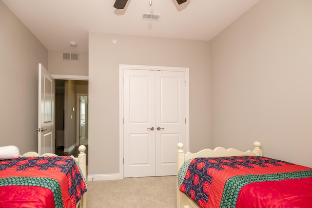 bedroom with a closet, visible vents, light colored carpet, and a ceiling fan